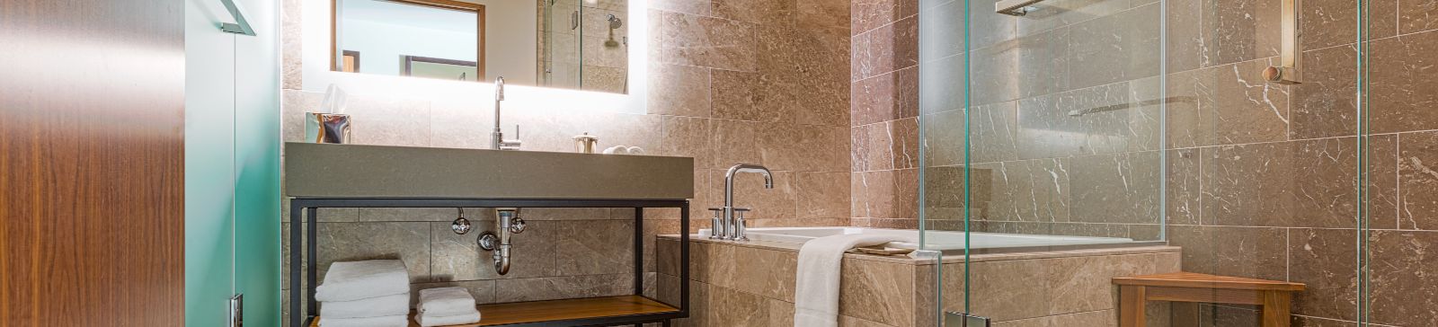 A view at marble tiled bathroom with a shower and a tub