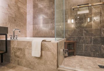 A view at marble tiled bathroom with a shower and a tub