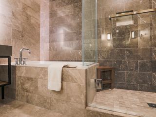 A view at marble tiled bathroom with a shower and a tub